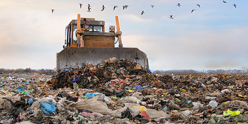 Bulldozer Working on Landfill With Birds in the Sky