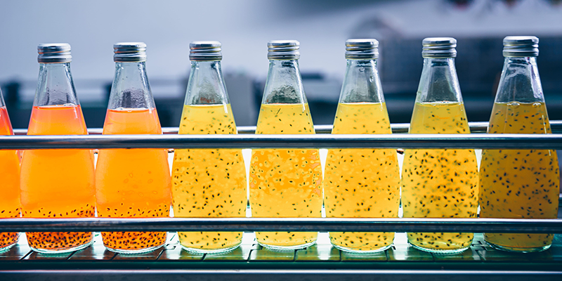 Factory Expansion Without More Water Supply Bottles Filled with Orange Liquid on a Conveyor Belt